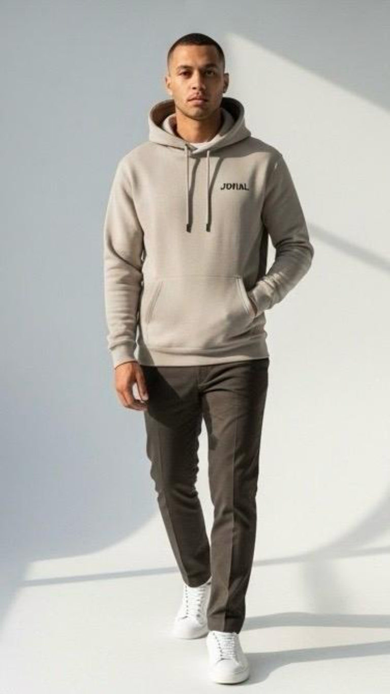 Man wearing a gray hoodie with 'Jovial' branding, dark pants, and white shoes on a light background