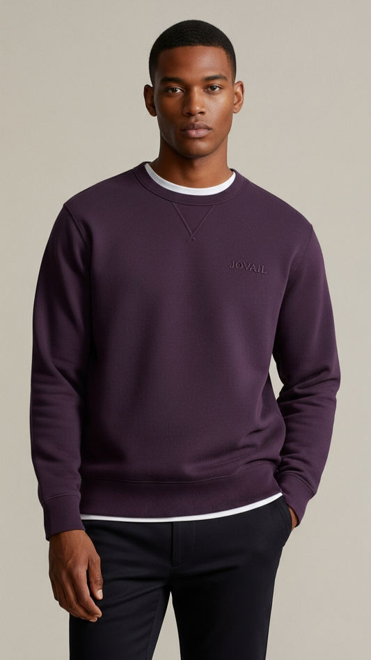 Man wearing a purple sweatshirt with a brand logo on a beige background