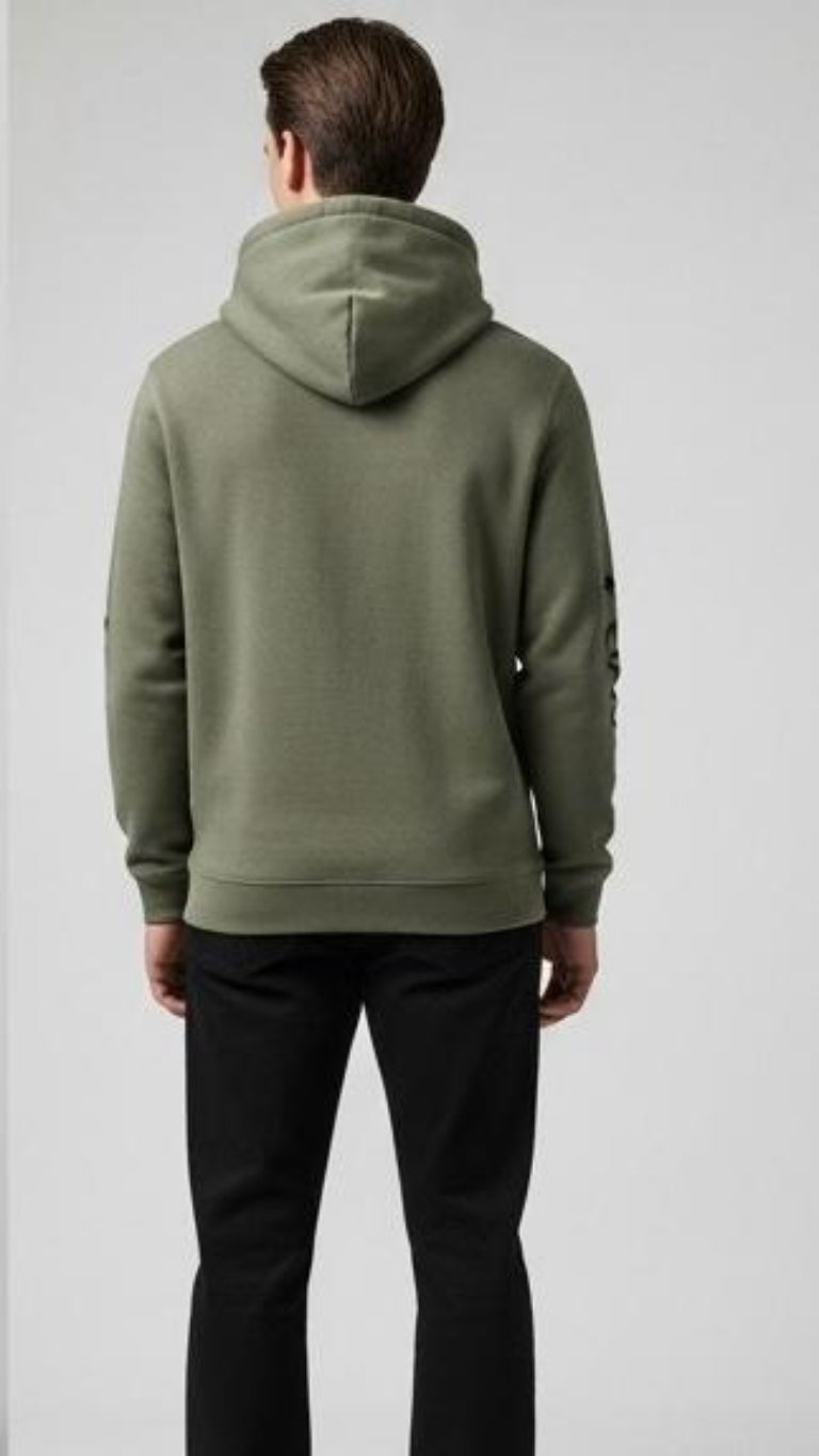 Person wearing a green hoodie and black pants on a white background