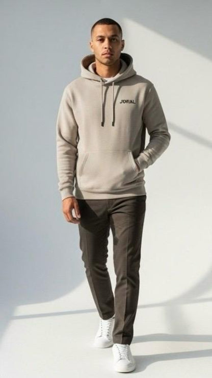 Man wearing a gray hoodie with 'Jovial' branding, dark pants, and white shoes on a light background